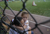 A woman embraces her young daughter as they spend time outdoors at a public park in the Gravesend section of Brooklyn, Monday, Sept. 28, 2020, in New York. The neighborhood has seen a recent uptick in COVID-19 cases. New York Gov. Andrew Cuomo raised alarms Monday about the emergence of a handful of coronavirus hot spots in New York, including the Gravesend neighborhood, saying just 10 ZIP codes represented more than a quarter of the state's new infections in recent testing. (AP Photo/Kathy Willens)