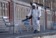 A member from a local veterinary service wearing protective suit sprays disinfectant on a platform of the railway station in Ladozhskoye Ozero village outside St. Petersburg, Russia, Saturday, April 4, 2020. The new coronavirus causes mild or moderate symptoms for most people, but for some, especially older adults and people with existing health problems, it can cause more severe illness or death. (AP Photo/Dmitri Lovetsky)