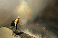 A firefighter watches as a wildfire burns Wednesday, Oct. 13, 2021, in Goleta, Calif. A wildfire raging through Southern California coastal mountains threatened ranches and rural homes and kept a major highway shut down Wednesday as the fire-scarred state faced a new round of dry winds that raise risk of flames. The Alisal Fire covered more than 22 square miles (57 square kilometers) in the Santa Ynez Mountains west of Santa Barbara. (AP Photo/Ringo H.W. Chiu)