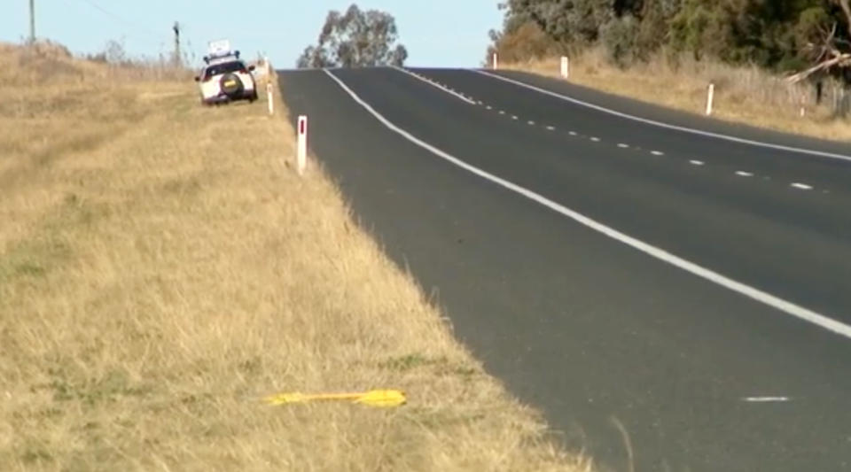 A warning sign lies on the ground with a speed check car in the distance - speeding fines