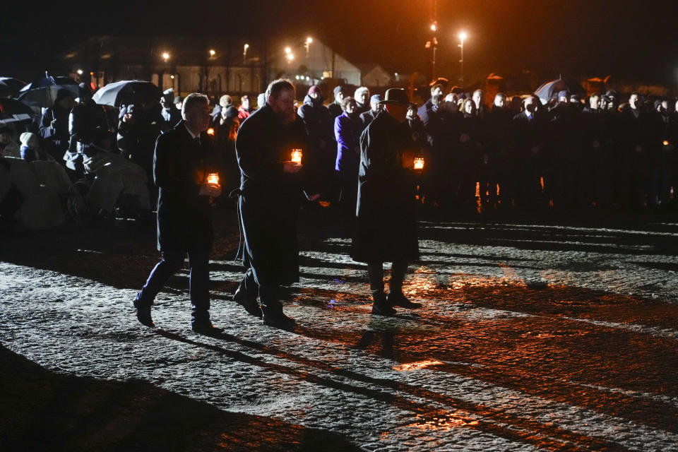 Director of the Auschwitz Museum Piotr Cywinski, center, along with other officials, take lit candles to the monument at the Birkenau Nazi death camp during a ceremony in Oswiecim, Poland, Saturday, Jan. 27, 2024. Survivors of Nazi death camps marked the 79th anniversary of the liberation of the Auschwitz-Birkenau camp during World War II in a ceremony in southern Poland.(AP Photo/Czarek Sokolowski)