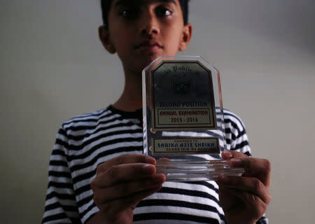 Ali Aziz Shaikh 12, brother of Sabika Aziz Sheikh, a Pakistani exchange student, who was killed with others when a gunman attacked Santa Fe High School in Santa Fe, Texas, U.S., poses for a photo with her shield prize at their residence in Karachi, Pakistan May 19, 2018. REUTERS/Akhtar Soomro