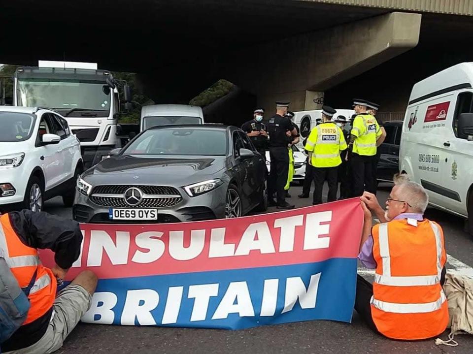 Police speak to one another as Insulate Britain protesters block an M25 junction (Insulate Britain/PA)