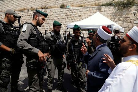 Palestinians speak to Israeli border police officers as they stand at a road block on a street heading to Lion's Gate at Jerusalem's Old city July 21, 2017. REUTERS/Ronen Zvulun