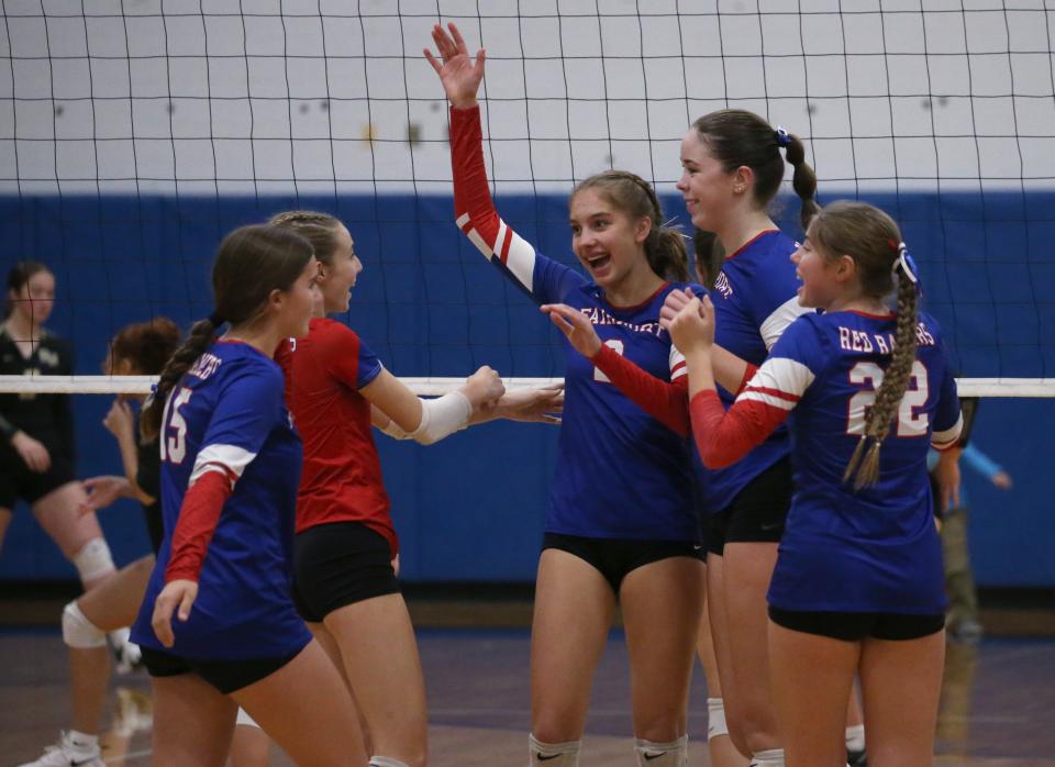 Fairport players celebrate after Kiera Cornman (2) scored with a spike at the net.