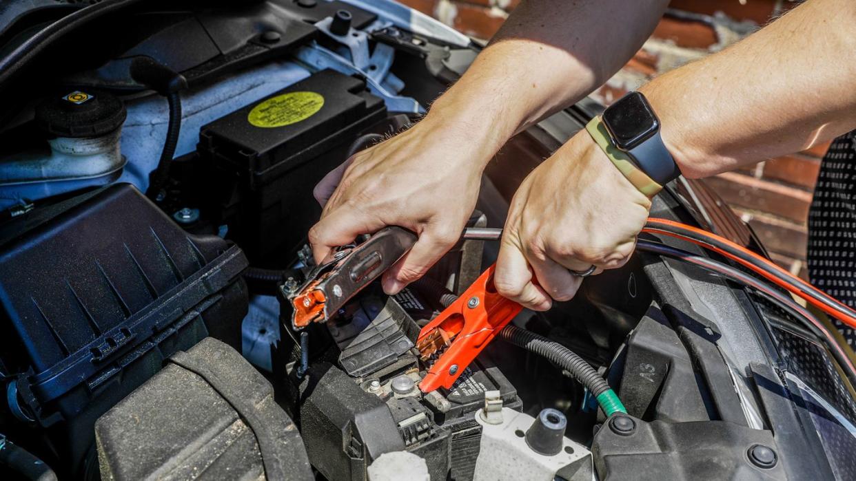 a person attaching jumper cables to a car