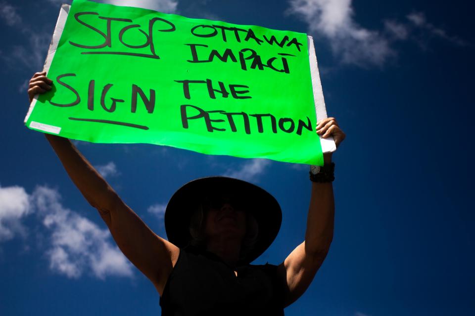 Peitioners hold signs calling for the recall petition for District Two Commissioner Lucy Ebel Monday, Aug. 28, 2023, on the corner of River and Douglas Ave in Holland.