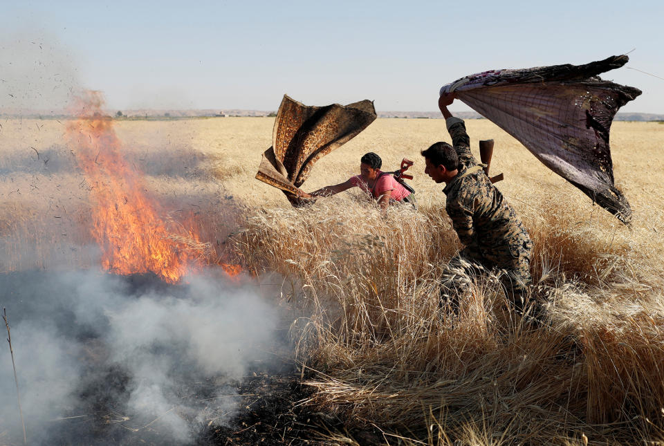 <p>Kurdish fighters from the People’s Protection Units (YPG) extinguish a fire in a wheat field burned during clashes with Islamic State militants in Raqqa, Syria, June 15, 2017. (Photo: Goran Tomasevic/Reuters) </p>