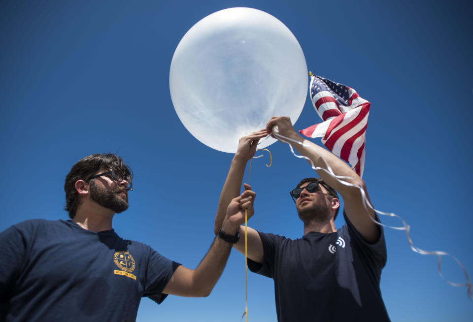 CORRECTS TO READ THAT TEAM LEADER IS TYING A STRING TO BALLOON - In this March 13, 2019 photo, Project OWL team leader Bryan Knouse ties a string to a helium-filled balloon carrying a tiny transmitter, aided by D.A. Koons, of the Information Technology Disaster Resource Center, during a field test in Isabela, Puerto Rico. Other tech companies have jumped at the opportunity to provide connectivity in the storm's aftermath, including Google, which obtained an experimental license from the U.S. Federal Communications Commission to provide emergency cellular service through Loon balloons. (AP Photo/Carlos Giusti)