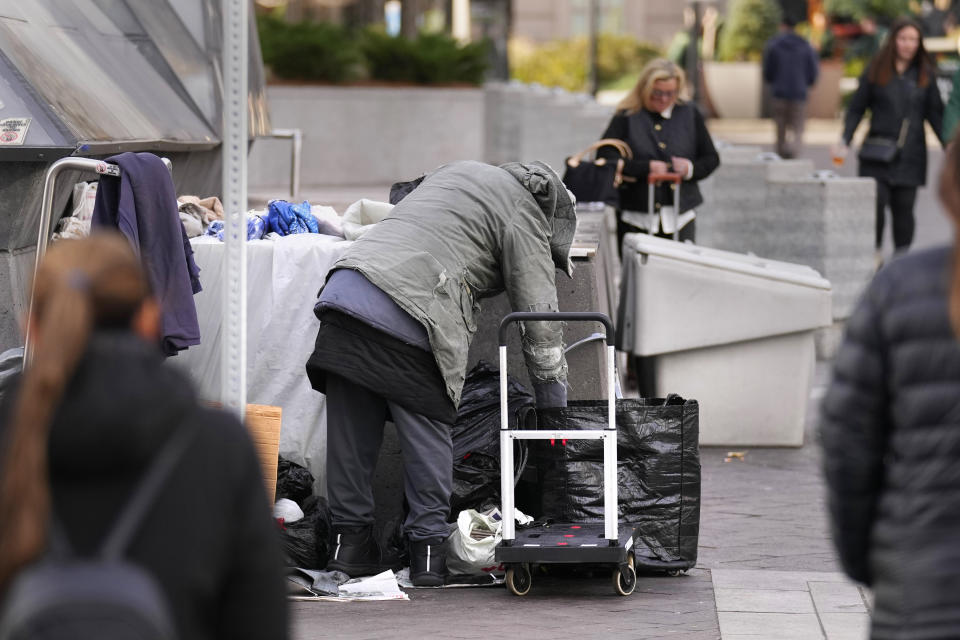 A homeless man repacks his belongings on a sidewalk outside South Station, Wednesday, Nov. 15, 2023, in Boston. Advocates scrambling to find shelter for homeless families newly arrived to Massachusetts say they're frustrated with the lack of good options after the state capped the number of shelter spots for homeless families and created a wait list. (AP Photo/Charles Krupa)
