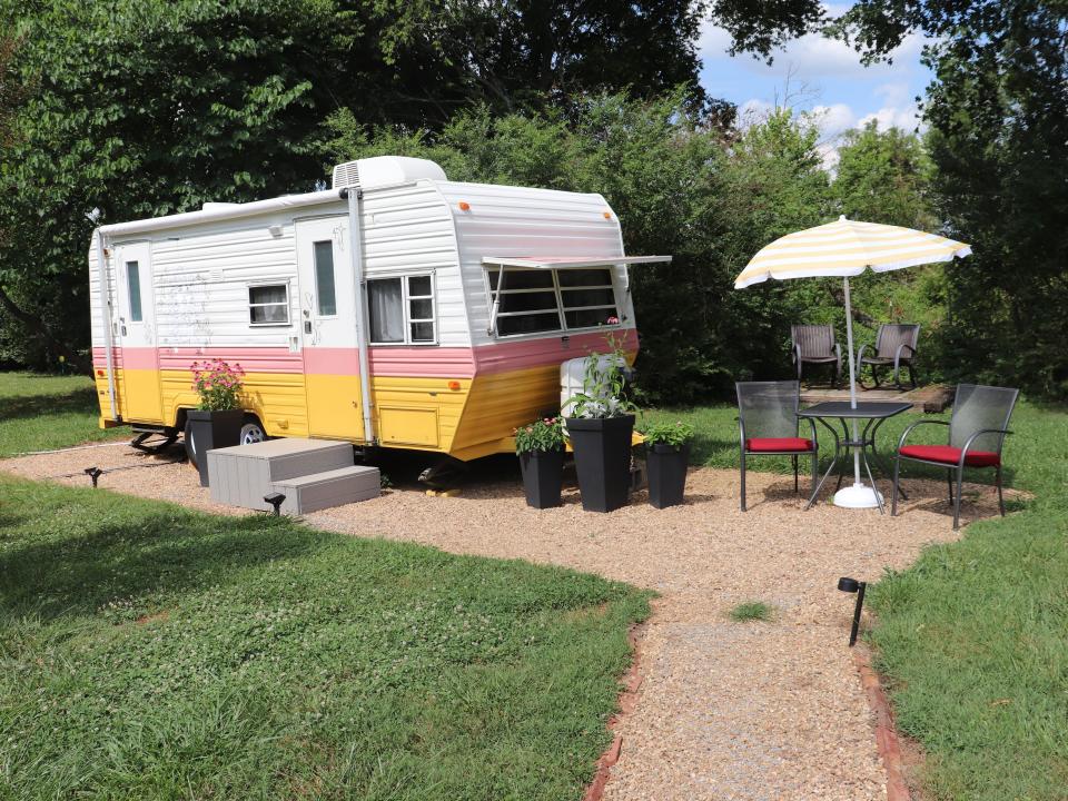 A Dolly Parton-themed RV on Airbnb with a small outdoor seating area next to it.