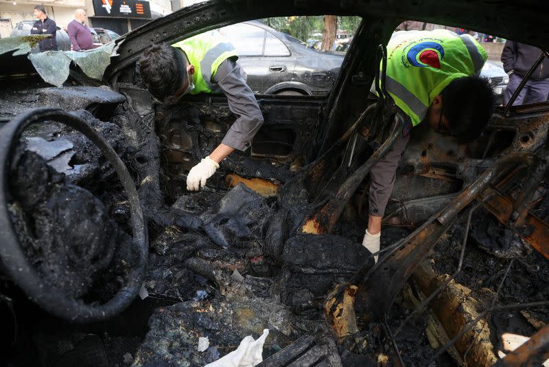 Miembros de la defensa civil comprueban un coche quemado tras lo que, según fuentes de seguridad, fue un ataque de un dron israelí en los suburbios de Dahiyeh, en el sur de Beirut