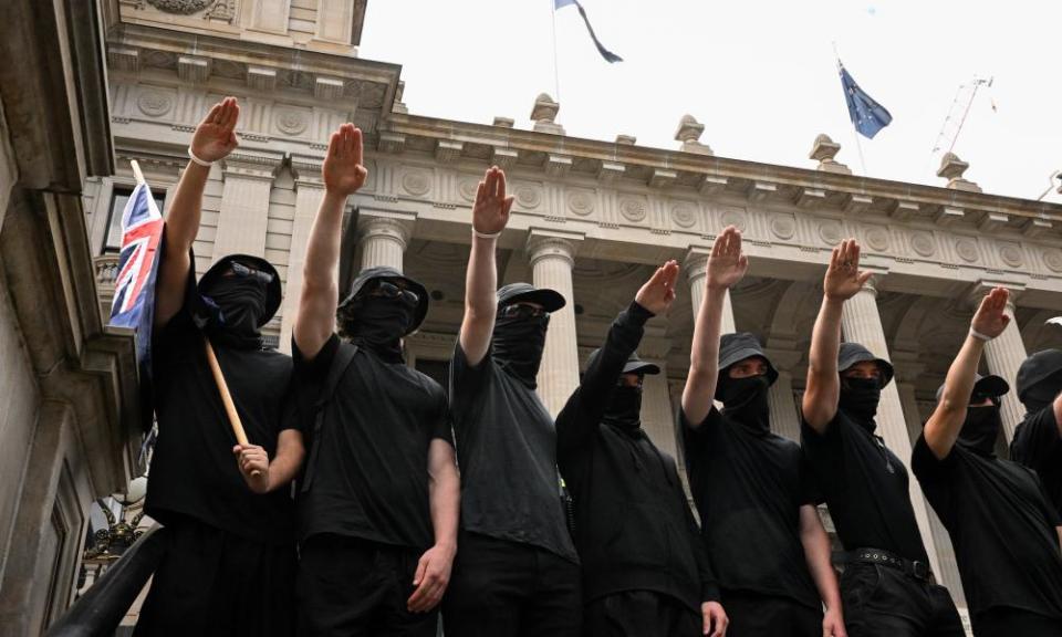 People wearing black with their faces covered make a nazi salute 