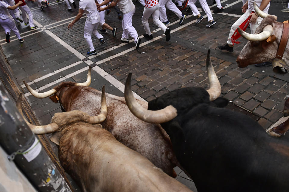People run through the streets with fighting bulls and steers during the first day of the running of the bulls at the San Fermin Festival in Pamplona, northern Spain, Thursday, July 7, 2022. Revellers from around the world flock to Pamplona every year for nine days of uninterrupted partying in Pamplona's famed running of the bulls festival which was suspended for the past two years because of the coronavirus pandemic. (AP Photo/Alvaro Barrientos)