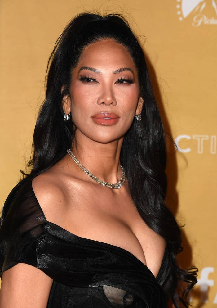 Celebrity Kimora Lee Simmons wearing a black off-the-shoulder gown with statement necklace