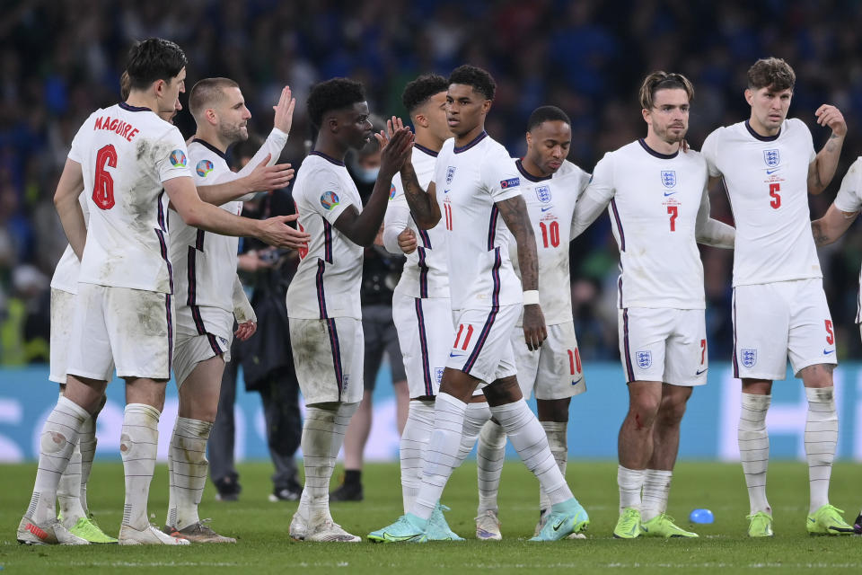 FILE - England's Harry Maguire, Luke Shaw and Bukayo Saka, from left, reach out to Marcus Rashford after he missed a penalty in the penalty shootout of the Euro 2020 soccer final match between England and Italy at Wembley stadium in London, Sunday, July 11, 2021. Black players like Marcus Rashford and Bukayo Saka have flourished even after being targeted online for missing penalties in England's shootout loss to Italy in the European Championship final in 2020. But a third Black player who also missed a penalty and was racially abused, Jadon Sancho, has struggled on the field ever since. (Laurence Griffiths/Pool via AP, File)