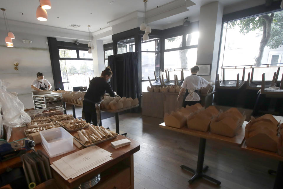 FILE - In this Friday, March 27, 2020 file photo, Nightbird Restaurant sous chef Bailey Walton, from left, chef and owner Kim Alter and pastry chef Hope Waggoner pack dinner boxes that were delivered to hospital workers in San FranciscoTaxpayers will pay restaurants to make three meals a day for California's millions of seniors during the coronavirus pandemic, Gov. Gavin Newsom announced Friday, April 24, 2020, putting the industry back to work and generating sales tax collections for cash-strapped local governments. California has about 5.7 million people 65 and older, but not all of them will be eligible, and some will have to meet income thresholds. (AP Photo/Jeff Chiu, File)