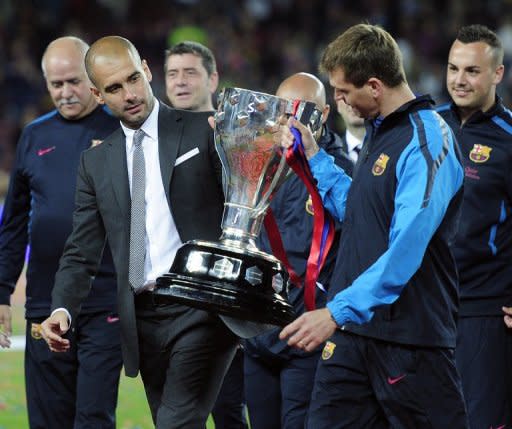 El por entonces entrenador del Barca, Pep Guardiola (I), porta el trofeo de Liga junto a su ayudante, Tito Vilanova, el 15 de mayo de 2011.