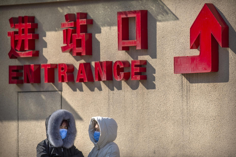 Travelers wear face masks as they stand outside the Beijing Railway Station in Beijing, Saturday, Feb. 15, 2020. People returning to Beijing will now have to isolate themselves either at home or in a concentrated area for medical observation, said a notice from the Chinese capital's prevention and control work group published by state media late Friday. (AP Photo/Mark Schiefelbein)