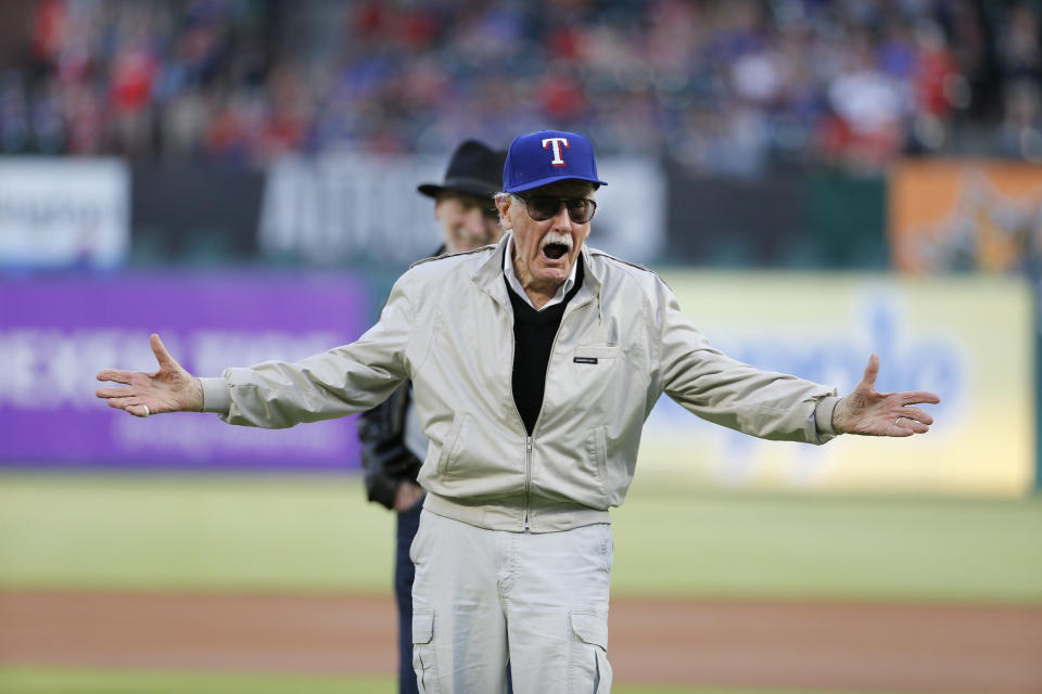 Stan Lee of Marvel Comics fame smiles after throwing out the ceremonial first pitch as Frank Miller, rear, a writer, director and actor, watches before a baseball game between the Seattle Mariners and Texas Rangers on June 4, 2016, in Arlington, Texas.