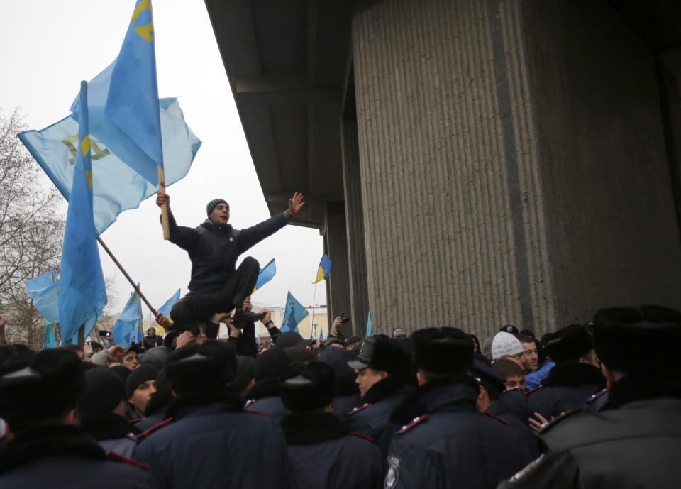 A Crimean Tatar shouts slogans and waves the ethnic flag of the Crimean Tatars during a protest in front of a local government building in Simferopol, Crimea, Ukraine, Wednesday, Feb. 26, 2014. More than 10,000 Muslim Tatars rallied in support of the interim government. That group clashed with a smaller pro-Russian rally nearby. Fistfights broke out between pro- and anti-Russian demonstrators in Ukraine's strategic Crimea region on Wednesday as Russian President Vladimir Putin ordered massive military exercises just across the border. (AP Photo/Darko Vojinovic)