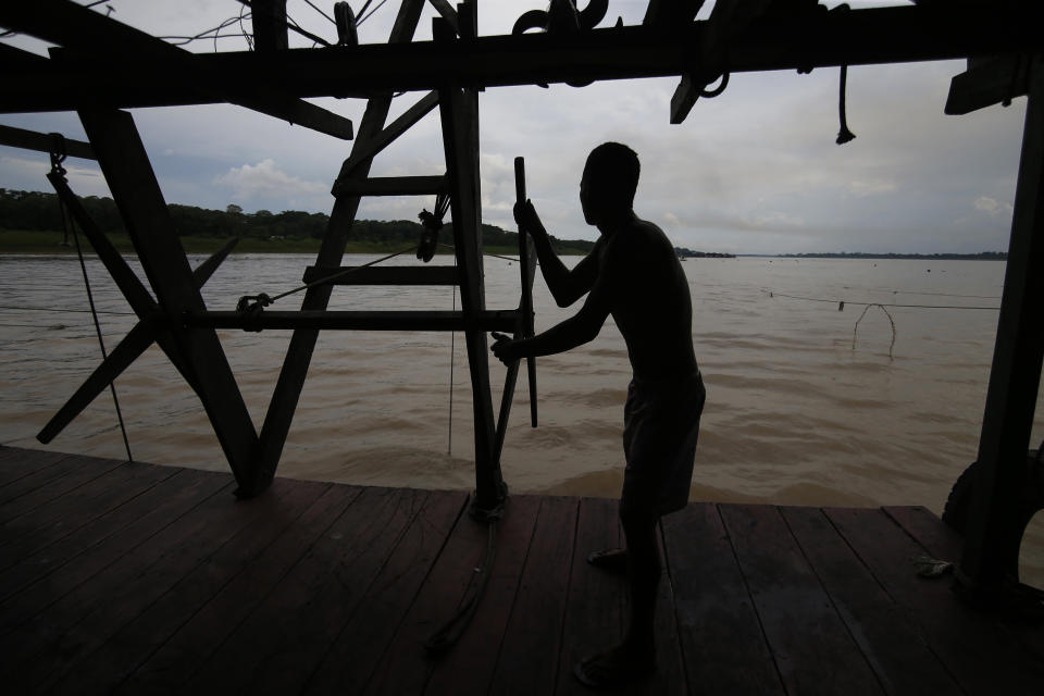 An illegal gold miner works on a dredging barge on the Madeira river, a tributary of the Amazon river, searching for gold, in Autazes, Amazonas state, Brazil, Thursday, Nov.25, 2021. Hundreds of mining barges have arrived during the past two weeks after rumors of gold spread, with environmentalists sounding the alarm about the unprecedented convergence of boats in the sensitive ecosystem. (AP Photo/Edmar Barros)