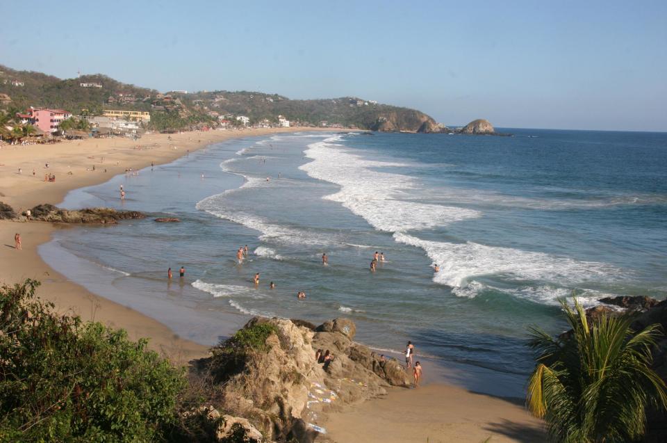 This Jan. 6, 2013 photo shows visitors bathing in the surf along the beach in Zipolite, Mexico. A sleepy town with one main street and no ATMs, Zipolite is one many tiny coastal pueblos that dot the Pacific in Mexico's Southern state of Oaxaca. (AP Photo/Jody Kurash)