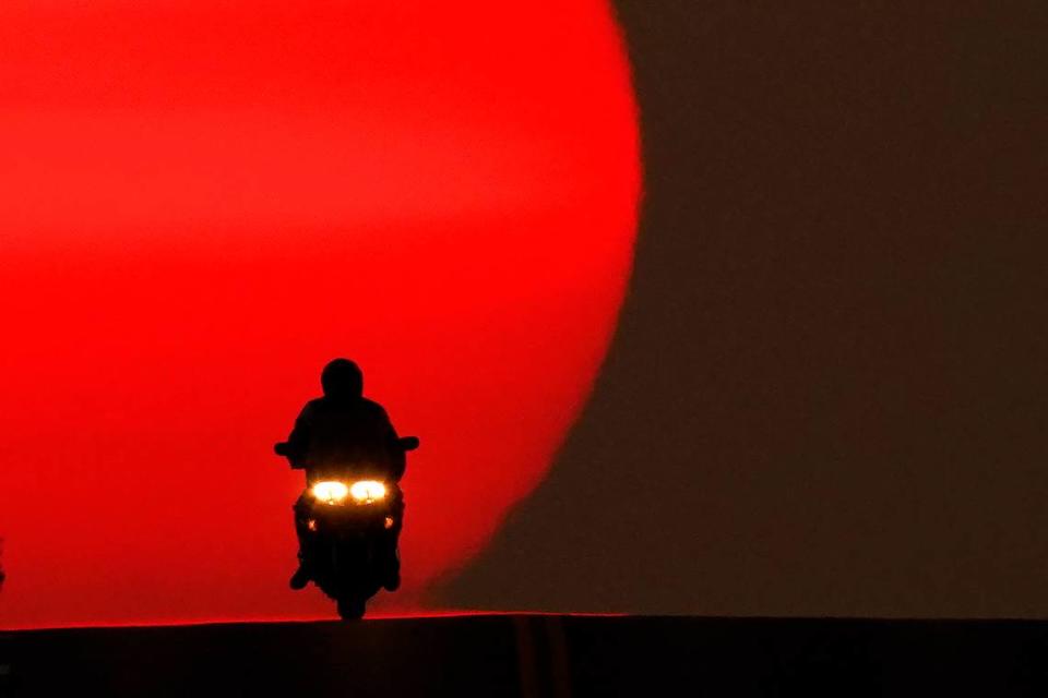 A motorcyclist is silhouetted against the setting sun Sunday in Shawnee. Sunsets have been more vibrant than normal recently as smoke from western wildfires drifts across the United States.