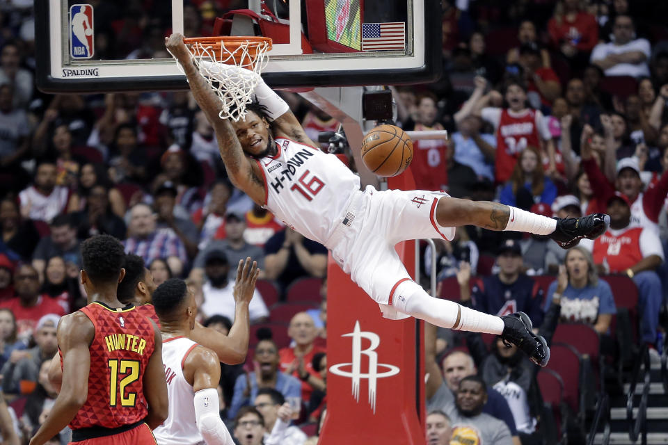 Houston Rockets guard Ben McLemore (16) hangs on the rim after his dunk as Atlanta Hawks forward De'Andre Hunter (12) looks on during the first half of an NBA basketball game, Saturday, Nov. 30, 2019, in Houston. (AP Photo/Michael Wyke)