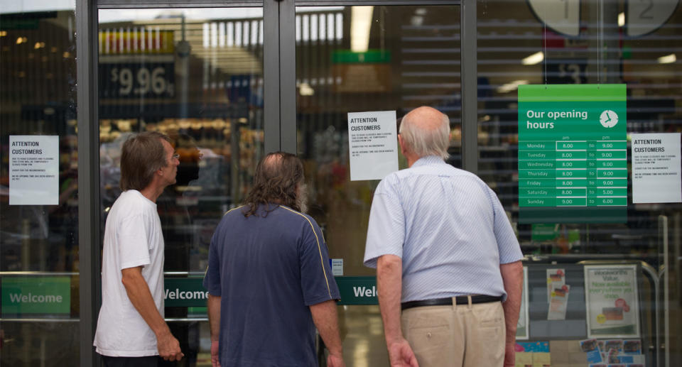 Photo shows customers standing outside a closed Woolworths store.