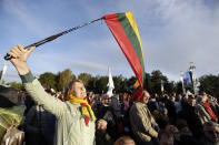 A woman holds a Lithuasnian flag as she waits for the arrival of Pope Francis to celebrate mass, at the Santakos Park, in Kaunas, Lithuania, Sunday, Sept. 23, 2018. (AP Photo/Andrew Medichini)