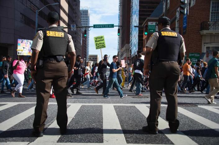 Police stand watch as protesters march through the streets in Baltimore on May 2, 2015, a day after six police officers were charged over the death of Freddie Gray (AFP Photo/Jim Watson)