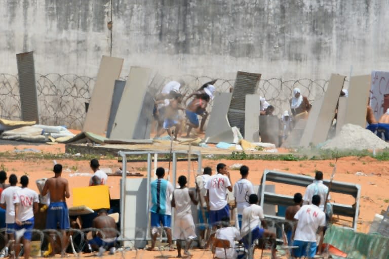 Prisoners use makeshift shields as riot police fire rubber bullets during a rebellion at the Alcacuz jail near the northeastern city of Natal on January 17, 2017