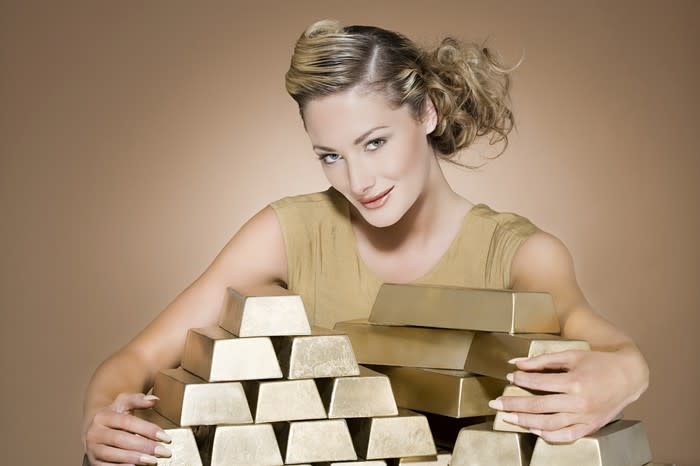 A woman with her arms wrapped around gold bars