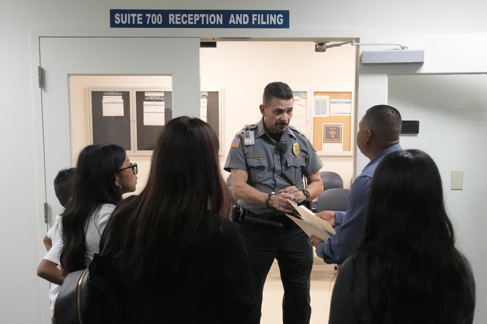 FILE - An officer listens to a question as he directs people to a courtroom, Jan. 10, 2024, in an immigration court in Miami. The number of international migrants who came to Miami-Dade County last year — more than 54,000 people — was the most in the U.S. Florida topped U.S. states with more than 178,000 international migrants last year, or 15% of the U.S. total. (AP Photo/Wilfredo Lee, file)