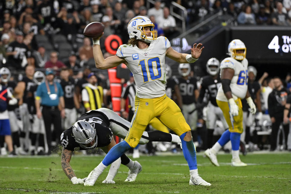 Los Angeles Chargers quarterback Justin Herbert (10) passes under pressure from Las Vegas Raiders defensive end Maxx Crosby (98) during the second half of an NFL football game, Sunday, Dec. 4, 2022, in Las Vegas. (AP Photo/David Becker)