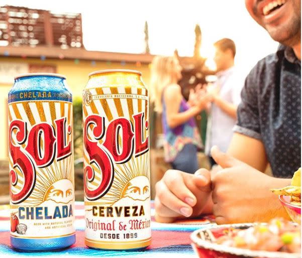 Man smiling in front of two beer cans