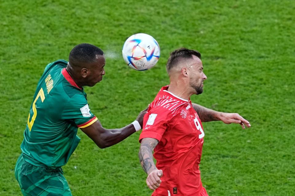 Cameroon's Gael Ondoua, left, jumps for a header with Switzerland's Haris Seferovic during the World Cup group G football match between Switzerland and Cameroon, at the Al Janoub Stadium in Al Wakrah, Qatar, Thursday, Nov. 24, 2022. (AP Photo/Ebrahim Noroozi)