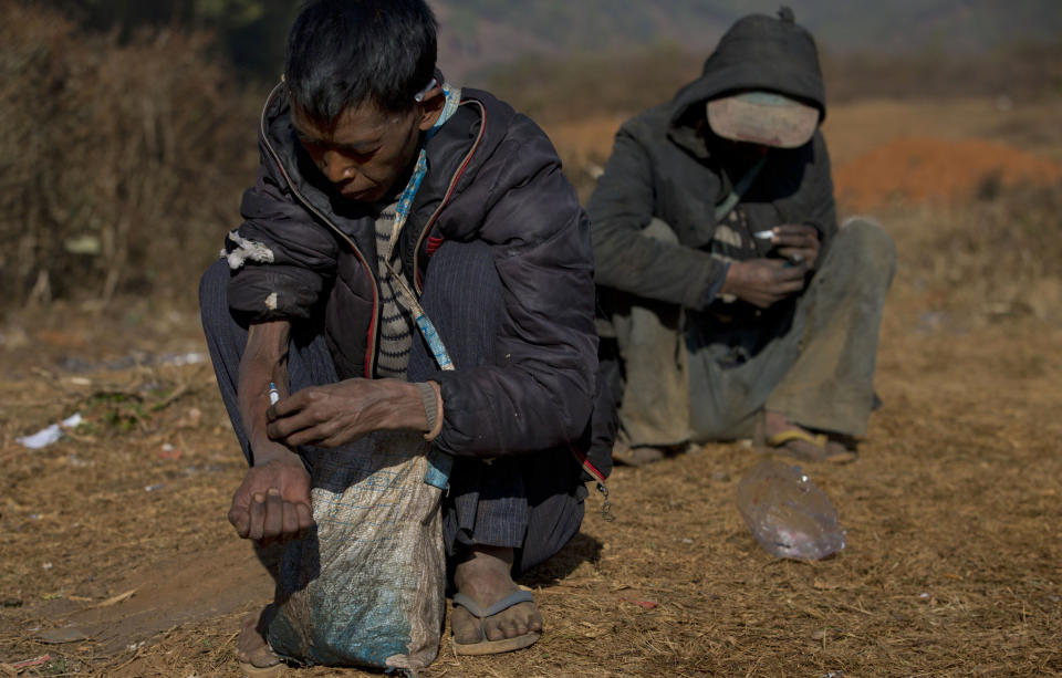 In this Jan 28, 2014 photo, addicts use needles at a cemetery in Nampatka village, northeastern Shan State, Myanmar. Every morning, more than 100 heroin and opium addicts descend on the graveyard to get high. Some junkies lean on white tombstones, tossing dirty needles and syringes into the dry, golden grass. Others squat on the ground, sucking from crude pipes fashioned from plastic water bottles. (AP Photo/Gemunu Amarasinghe)