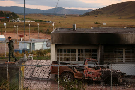 A venezuelan soldier walks next to a vehicle that was set ablaze at a guard post at the border between Venezuela and Brazil in Pacaraima, Roraima state, Brazil February 24, 2019. REUTERS/Bruno Kelly