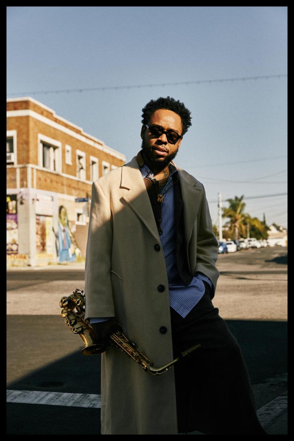 Terrace Martin stands in a crosswalk, a low-slung brick building behind him