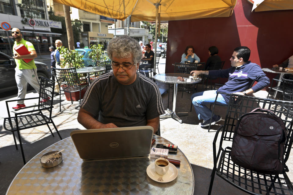 In this Friday, April 18, 2014 photo, Syrian novelist Khaled Khalifa writes a commentary for the pan-Arab daily newspaper Al-Hayat on the death of Colombian novelist Gabriel Garcia Marquez, at a cafe in Hamra Street, Beirut, Lebanon. Khalifa’s thoughts keep wandering back to his home and favorite place in the world, the northern city of Aleppo, Syria. For nearly two years now, Aleppo has been ravaged by brutal urban warfare between rebels and government forces, each holding roughly half the city. (AP Photo/Bilal Hussein)