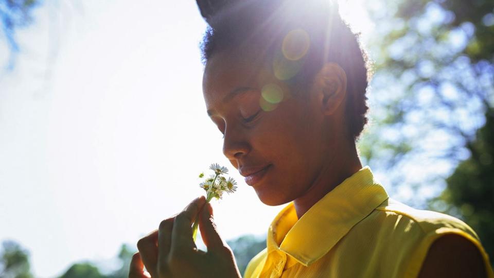 Women sniffs a flower on a summer's day