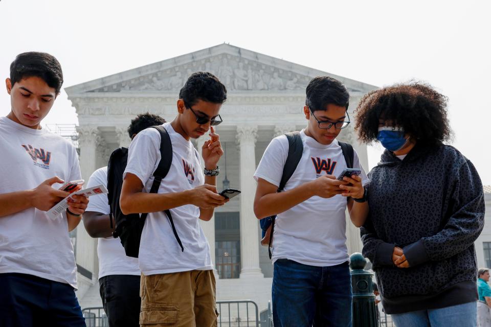 Students from Washington Adventist University look at their phones as news of the Supreme Court's decision pertaining to affirmative action is released outside the U.S. Supreme Court Building on June 29, 2023 in Washington, DC.