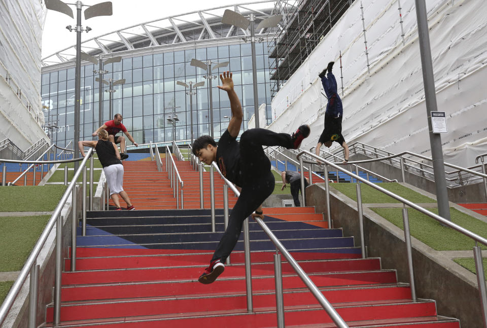 FILE - In this Aug. 16, 2018, file photo, participants of the Parkour Generations work on their practice runs outside of Wembley Stadium ahead of the 13th Rendezvous International Parkour Gathering in London. Global organizers of parkour are urging the IOC not to add the street-running sport to the 2024 Paris Olympics at a meeting next week. The Parkour Earth group has for years opposed what it calls a “hostile takeover” of the sport by the Olympic-recognized International Gymnastics Federation. Parkour Earth said Tuesday, Dec. 1, 2020 in an open letter to the International Olympic Committee that the world gymnastic body's "encroachment and misappropriation of our sport continues.” (AP Photo/Nishat Ahmed, File)