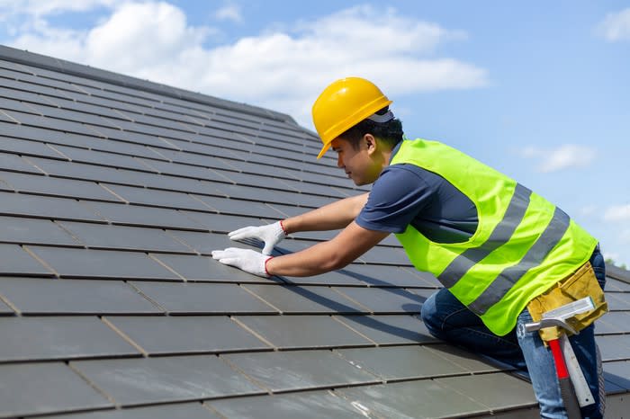 Worker installing shingles on a roof.