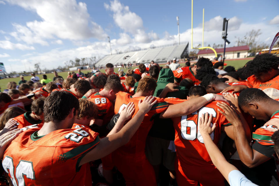 Coaches and players from Mosley High pray together after their loss to Pensacola High, in the aftermath of Hurricane Michael in Panama City, Fla., Saturday, Oct. 20, 2018. (AP Photo/Gerald Herbert)