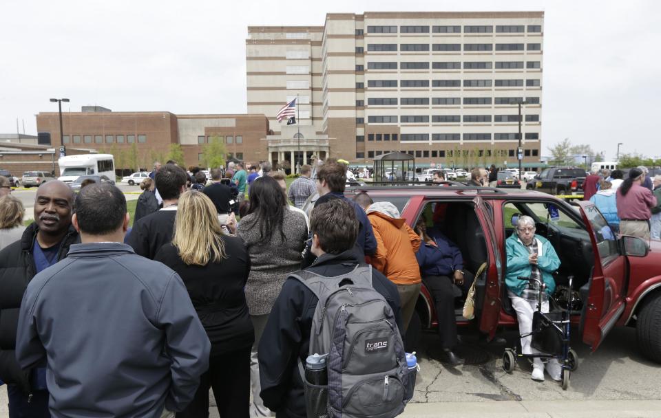 People stand outside a Veterans Affairs hospital after they were evacuated, Monday, May 5, 2014, in Dayton, Ohio. A city official says a suspect is in police custody after a shooting at the Veterans Affairs hospital in Ohio that left one person with a minor injury. (AP Photo/Al Behrman)