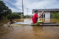 People use a makeshift raft to cross through a flooded village in Banjar, South Kalimantan on Borneo Island, Indonesia, in this Saturday, Jan. 16, 2021 photo. Many thousands of people have been evacuated and a number have been killed in recent days in flooding on Indonesia's Borneo island, officials said Sunday. (AP Photo/Putra)