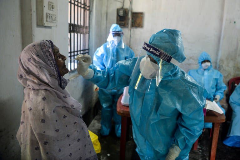 Un agent de santé effectue un prélèvement sur une femme en vue d'un test de Covid-19 à Siliguri (Inde) le 29 août 2020 - DIPTENDU DUTTA © 2019 AFP